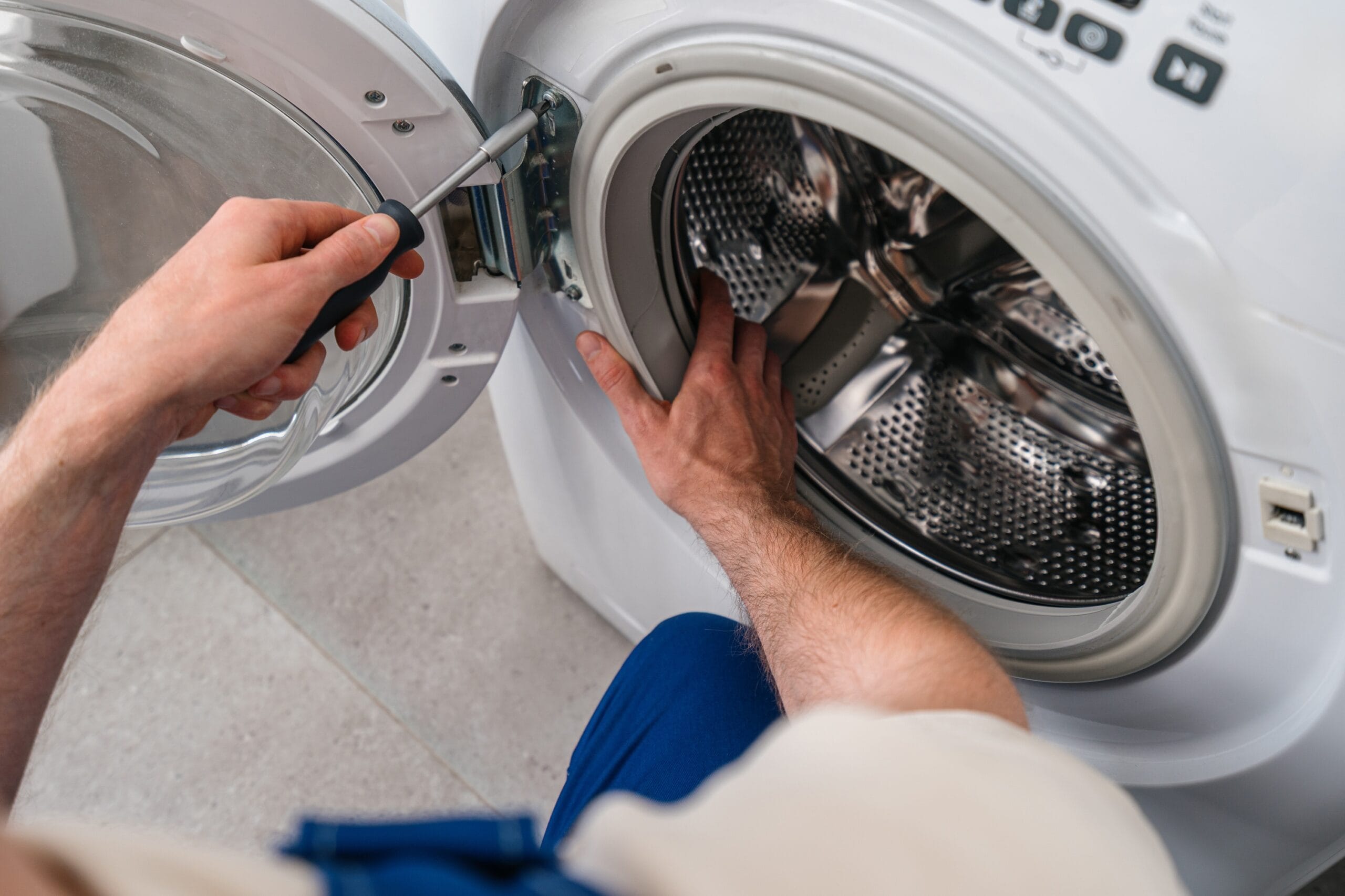 Home repair service fixing a washing machine in a modern laundry room